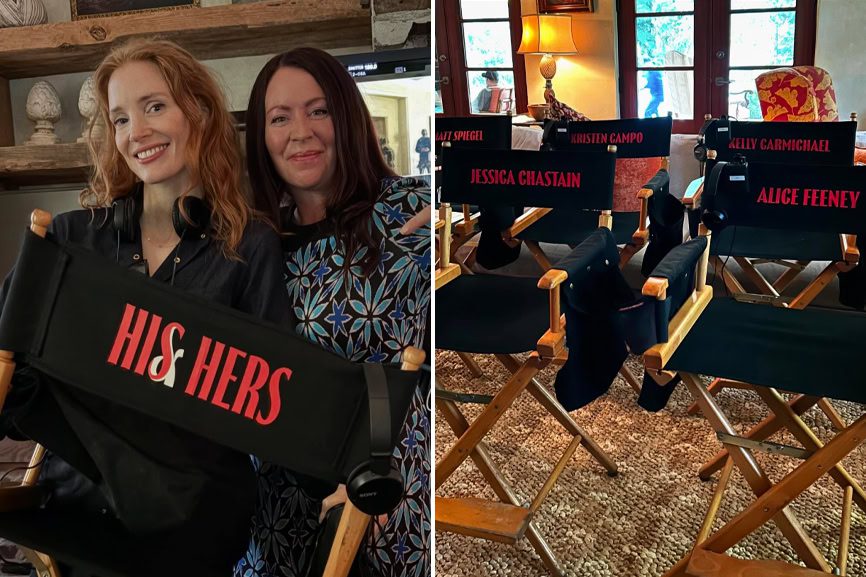 Red-haired woman and woman with dark hair smiling at an event, holding a director's chair with "HIS & HER'S" written on it; cozy rustic interior background.